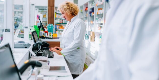 descuadres-caja-farmacia Farmacéutica haciendo cobros en una farmacia atenta para evitar descuadres en el cierre de caja
