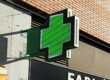 Cruz LED instalada en la fachada de una farmacia moderna.