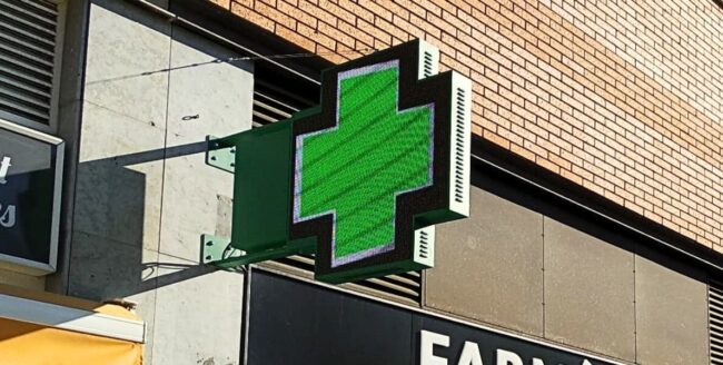 Cruz LED instalada en la fachada de una farmacia moderna.