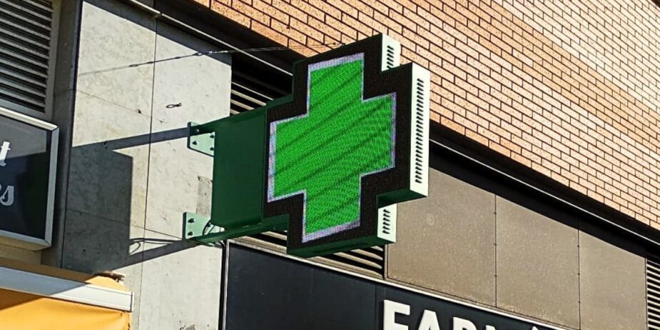 Cruz LED instalada en la fachada de una farmacia moderna.